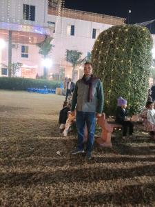 a man standing next to a park bench at night at Hotel Kunj Palace in Etah