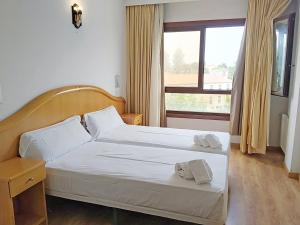 ein Schlafzimmer mit einem Bett, auf dem zwei Handtücher liegen in der Unterkunft Hotel Herbiña 3000 in Cambados