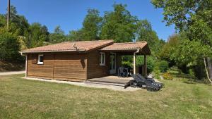 a small cabin with a deck in a yard at Le Verdoyant in Thenon