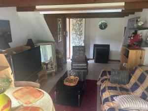 a living room with a flat screen tv and chairs at Hortensia in Carnoët