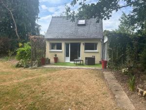 a small white house with a bench in the yard at Hortensia in Carnoët