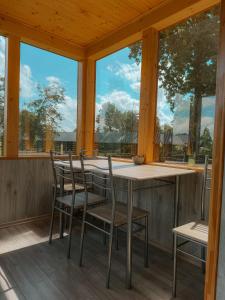 a table and chairs on a porch with windows at Ligzdiņas in Bernāti