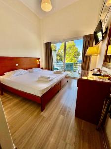 a bedroom with a large bed and a large window at Hotel Akti in Loutraki