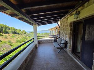 a balcony of a house with a chair on it at Lithos Villas Komitsa in Metókhion Koumítsas