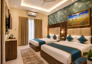 a hotel room with two beds and a painting on the wall at Hotel Smart Premier -Delhi Airport in Behror