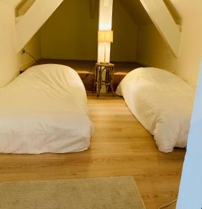 two white beds sitting on a wooden floor in a room at De Lotuspoort met Mihr's rustplek in de Abdij van Bornem in Bornem