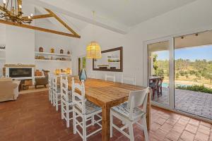 a dining room with a wooden table and white chairs at Monte Do Poço Country House in Erra