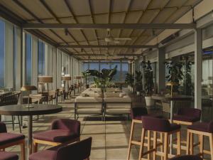 a restaurant with tables and chairs and windows at Meliá Barcelona Sky 4 Sup in Barcelona