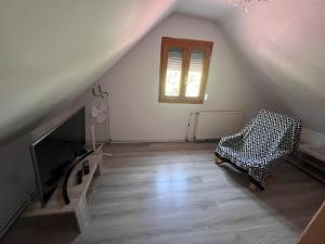 an attic room with a fireplace and a chair at BLTN House in Balatonalmádi +3 photos