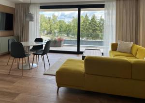 a living room with a yellow couch and a table at Apartmány Panoráma Bojnice in Bojnice