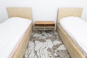 two beds in a room with a table between them at Garden View Apartment in Rrushkull