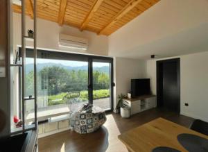 a living room with a large window and a television at Engadin Mountain Kucica in Brda