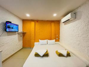 a room with a bed with two pillows and a tv at Nina's Aqua - Private Pool Villa & Plunge Pool Studios, Anjuna in Anjuna +190 photos