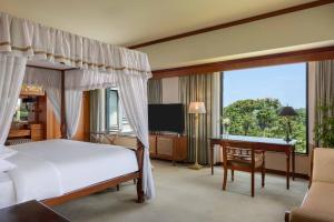 a bedroom with a bed and a desk and a television at Hyatt Regency Yogyakarta in Yogyakarta