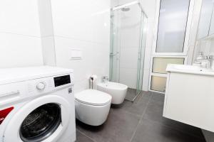 a white bathroom with a washing machine and a toilet at Garden View Apartment in Rrushkull +11 photos