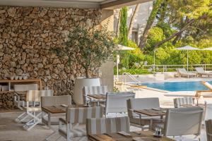 a patio with tables and chairs next to a pool at Maestral Adults Exclusive Hotel in Brela