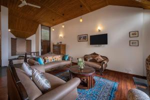 a living room with couches and a flat screen tv at Villa Harrington in Barog