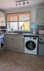a kitchen with a sink and a washing machine at Mach House in Campbeltown