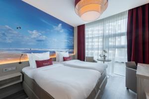 two beds in a hotel room with a view of the ocean at Ramada The Hague Scheveningen in Scheveningen
