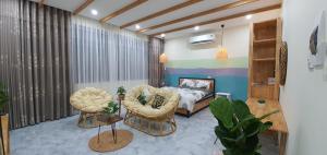 a bedroom with a bed and a couch and chairs at Bee House in Long Thủy