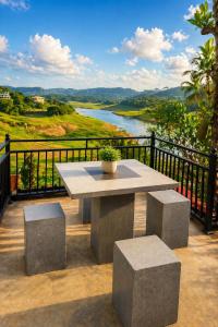 a table and benches on a balcony with a view of a river at The Don Dock Kandy in Kandy