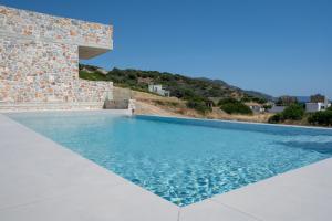 a swimming pool with blue water in front of a stone building at Stone Luxury Suites in Agioi Apostoli