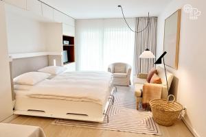 a white bedroom with a bed and a living room at Vier Häuser in Norderney