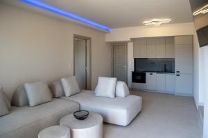 a living room with a white couch and a kitchen at Stone Luxury Suites in Agioi Apostoli