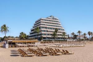 a beach with lounge chairs and a large building at ME by Meliá Sitges Terramar in Sitges +75 photos