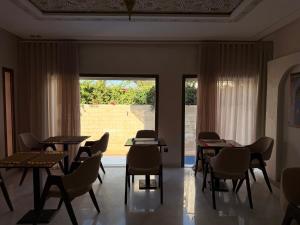 a dining room with tables and chairs and a large window at Riad Villa Elizabeth in Nouaseur