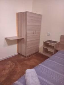 a bedroom with a bed and a wooden cabinet at Red Rocks Accommodation in Northam +1 photo