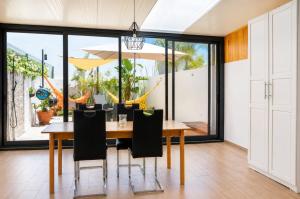 a dining room with a wooden table and black chairs at Casa Elegante V3 Moderna 2 Suítes, Jardim e Garagem Privados in Olhão