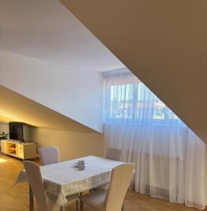 a dining room with a table and chairs and a window at Family rest apartments in Nikšić