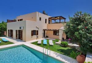 a villa with a swimming pool in front of a house at Villa Argiro Plaka Crete in Plaka
