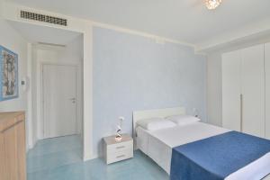 a white bedroom with a white bed and a blue floor at Agropoli Palace in Agropoli