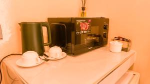 a microwave sitting on top of a counter with cups and saucers at Kendwa Stay in Kendwa