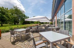 an outdoor patio with tables and chairs and an umbrella at Radisson Hotel, Fürst Leopold Dessau in Dessau