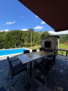 a table and chairs on a patio with a fireplace at Villa Pjene in Konjic