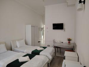 two beds in a room with a table and a sink at Chevrolet Hotel in Namangan