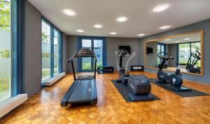 a gym with treadmills and ellipticals in a room with windows at Radisson Hotel, Fürst Leopold Dessau in Dessau