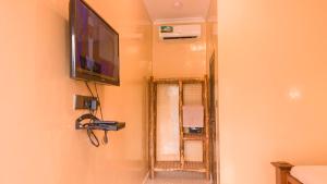 a flat screen tv hanging on a wall with a mirror at Kendwa Stay in Kendwa