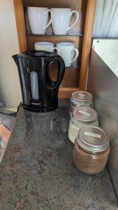 a coffee maker sitting on a counter with cups and jars at Mikael's Bed & Spa - Camping Suite in Sandefjord