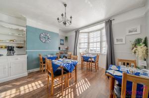 a dining room with tables and chairs and a clock on the wall at Lyndale Guest House in Weymouth