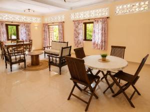 a living room with a table and chairs and a piano at Appartement Baie-Rose SP Nosy-Be in Nosy Be