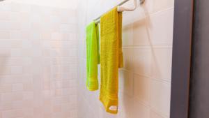a bathroom with green and yellow towels on a rack at Kendwa Stay in Kendwa +15 photos