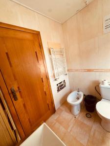 a bathroom with a toilet and a wooden door at Gama Barros 22 in Charneca