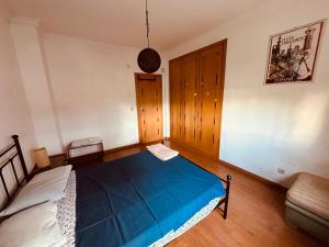 a bedroom with a blue bed and a couch at Gama Barros 22 in Charneca