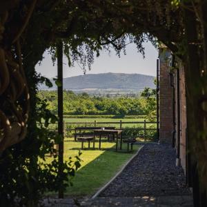 a patio with a table and benches in the grass at The Haughmond in Upton Magna