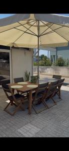a wooden table and chairs under an umbrella at Barcelos Residence Living in Barcelos