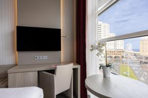 a living room with a table and a large window at Ramada The Hague Scheveningen in Scheveningen